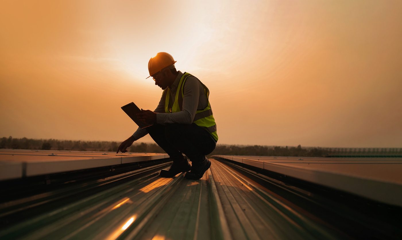 Engineer inspecting a commercial solar array at sunset